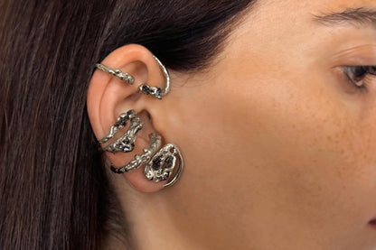 Close-up of a person wearing sterling silver wrap earring with black stones