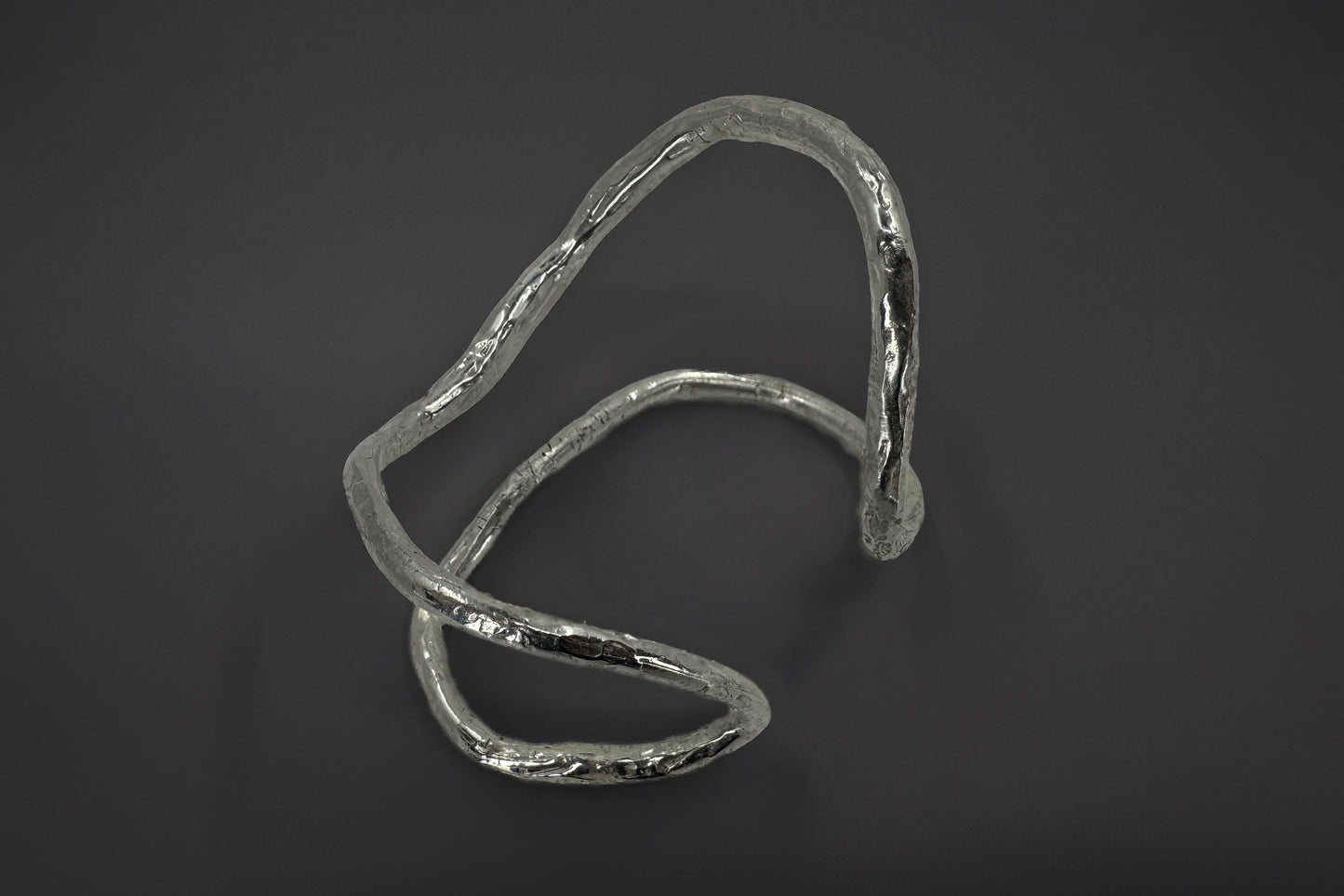 Sterling silver palm bracelet with a wavy design on a dark background