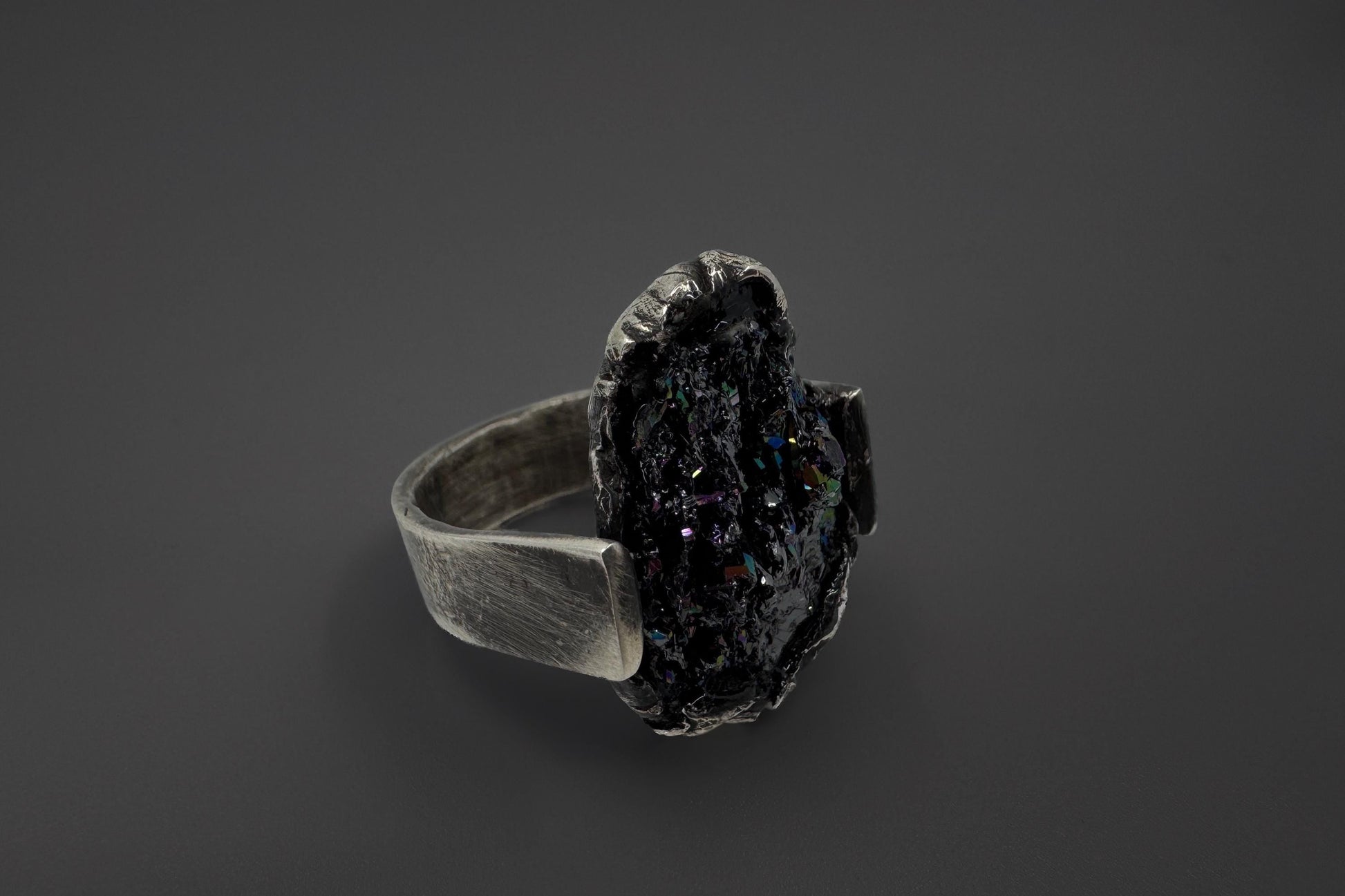 Silver ring with a dark stone on a black background