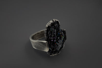 Silver ring with a dark stone on a black background